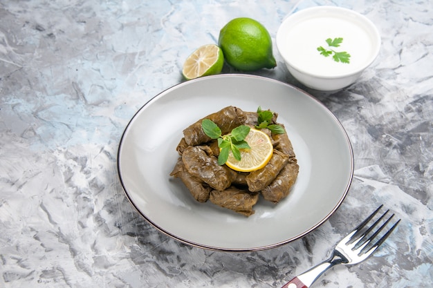 Front view of green leaf dolma with lemon on white surface