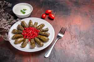 Free photo front view of green leaf dolma with pomegranates on dark surface