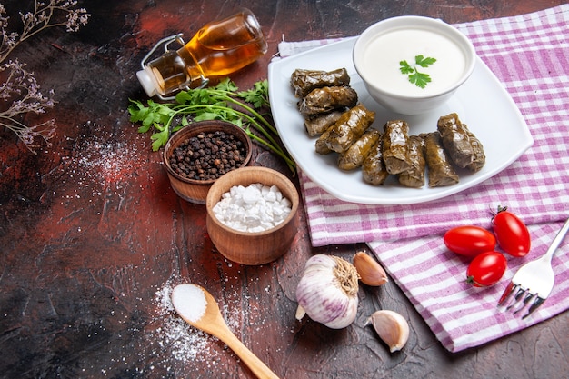 Front view of green leaf dolma with yogurt on dark surface