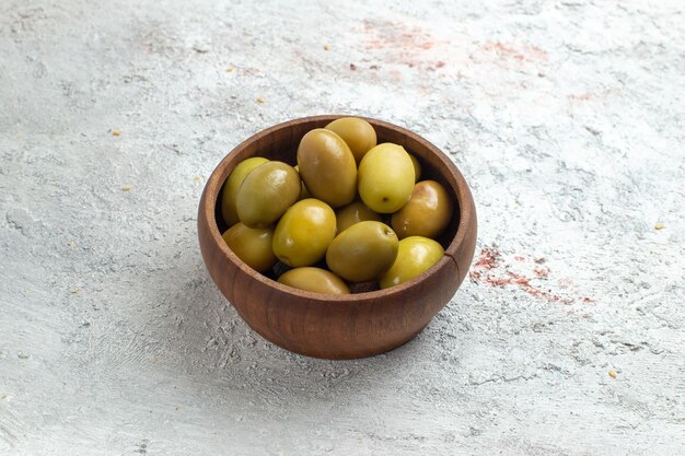 Зеленые оливки, вид спереди, внутри маленькой тарелки на белом пространстве