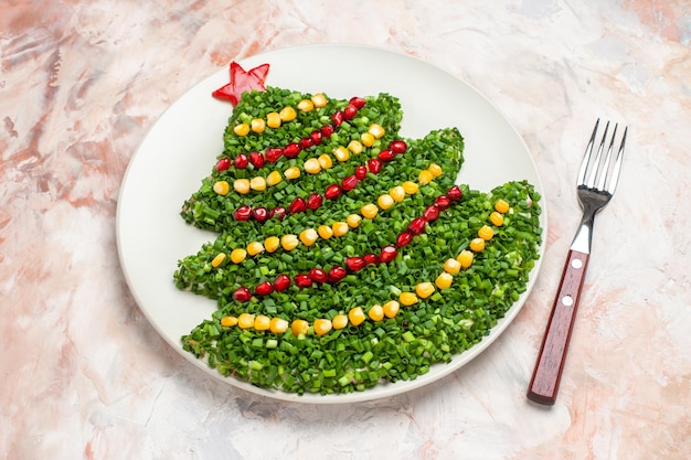 Вид спереди зеленый салат в форме новогодней елки внутри тарелки на светлом фоне