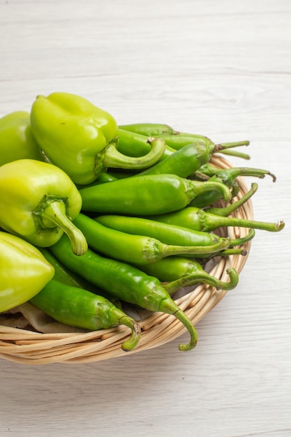 Front view green spicy peppers with bell-peppers inside basket on a white background color hot edgy vegetable salad photo ripe