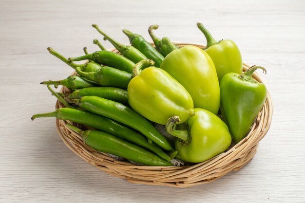 Front view green spicy peppers with bell-peppers inside basket on white background color hot edgy vegetable salad photo ripe