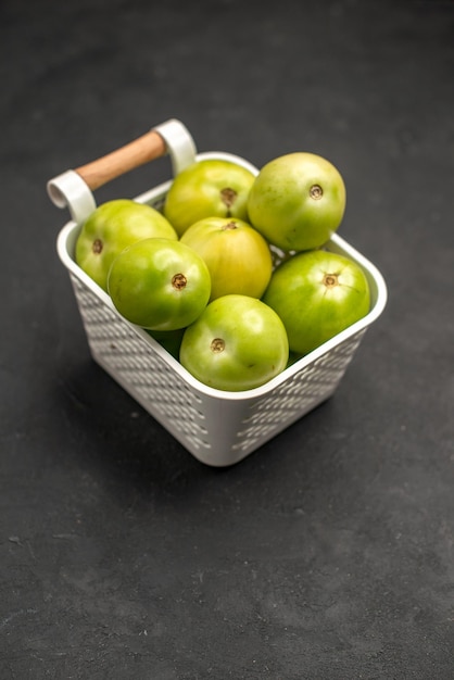 Front view green tomatoes inside basket on dark background