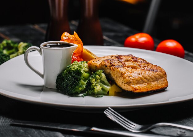 Front view grilled fish steak with broccoli and pomegranate sauce