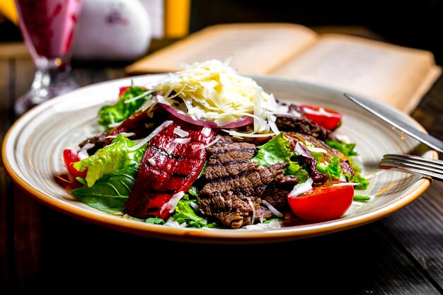 正面に野菜と肉のグリルと皿にすりおろしたチーズとレタス