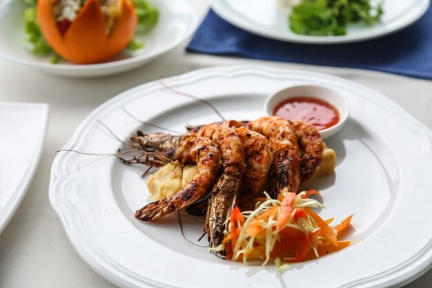 Front view grilled shrimp with chopped carrots with sauce on a plate