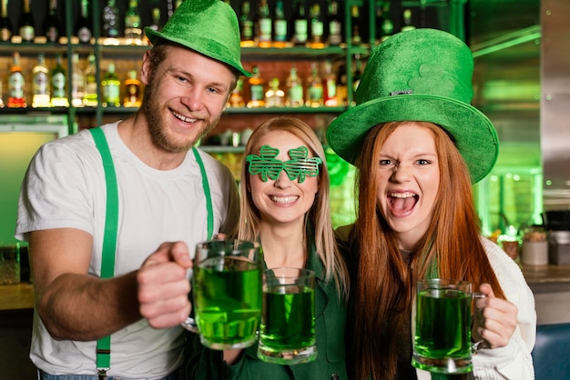 Front view of group of friends celebrating st. patrick's day with drinks