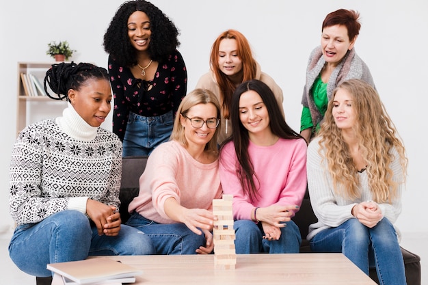 Front view group of friends playing together a wooden tower game