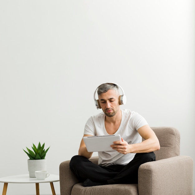 Free photo front view guy with headphones looking at his tablet