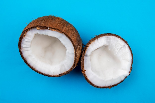 Foto gratuita vista frontale della metà di grandi noci di cocco marroni fresche sulla superficie del blu