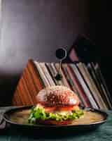 Free photo a front view hamburger inside round plate on the dark floor