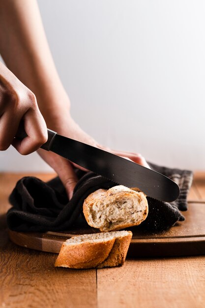 Front view of hand cutting a baguette on a chopper