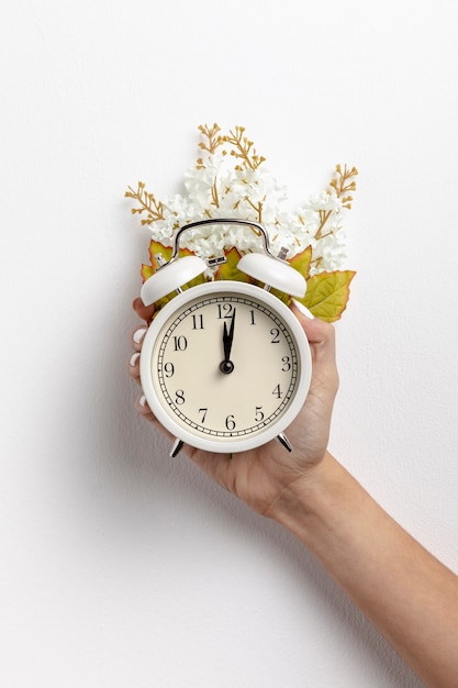 Free photo front view of hand held clock with flower and leaves