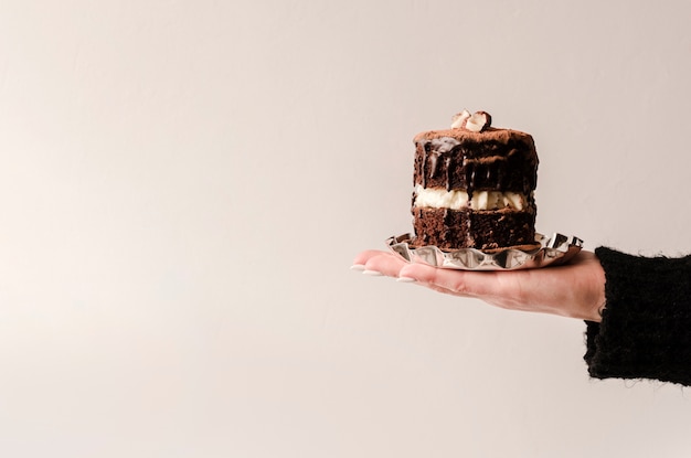 Front view of hand holding cake with copy space