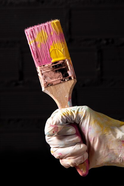 Front view of hand holding colored paint brush