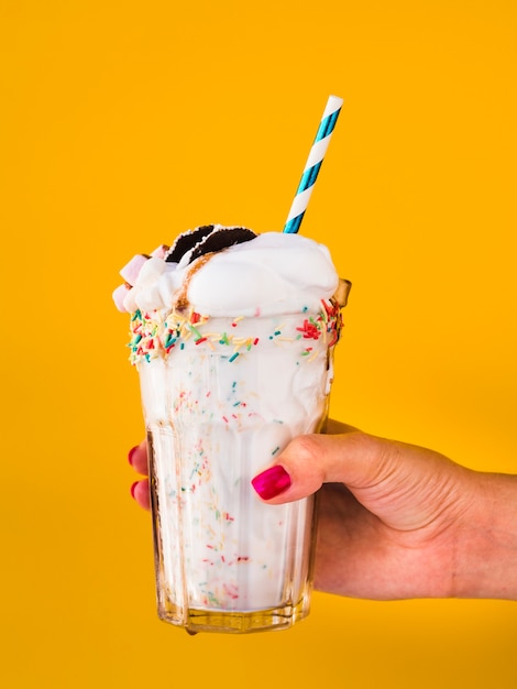 Free photo front view of hand holding a delicious milkshake