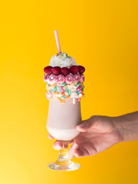 Front view of a hand holding a glass of milkshake