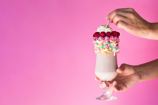 Front view of a hand holding a glass with milkshake