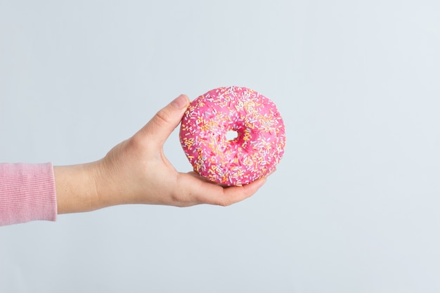 Front view of hand holding glazed doughnut with sprinkles