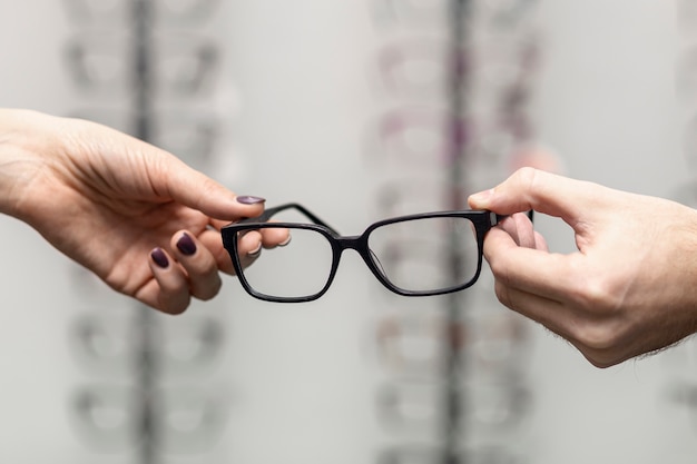 Front view of hand holding on to pair of glasses