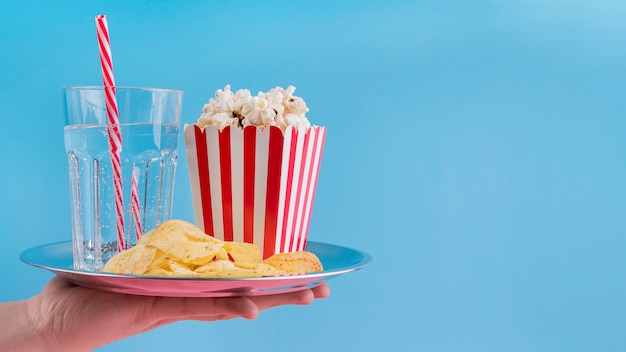 Free photo front view hand holding plate with snacks and copy-space