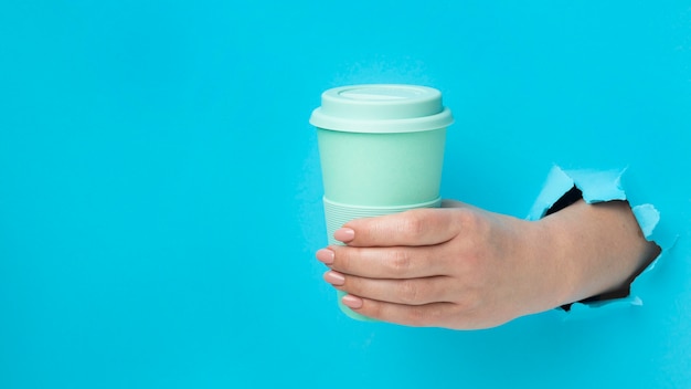 Front view hand holding reusable cup with copy space