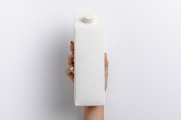 Free photo front view of hand holding simple milk carton