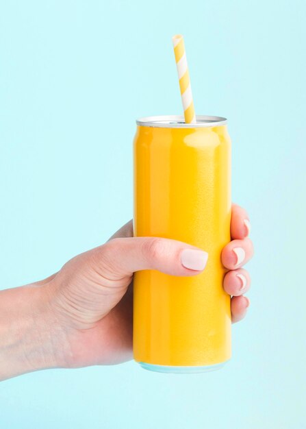 Front view of hand holding soft drink can with straw