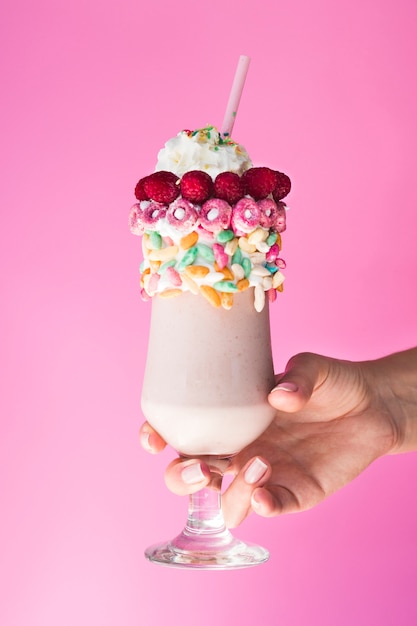 Front view of a hand and milkshape on pink background