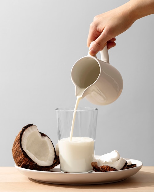 Вид спереди руки наливает кокосовое молоко в стакан