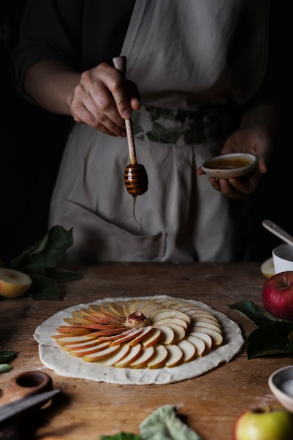 Foto gratuita miele di versamento della mano di vista frontale sulle fette di mela