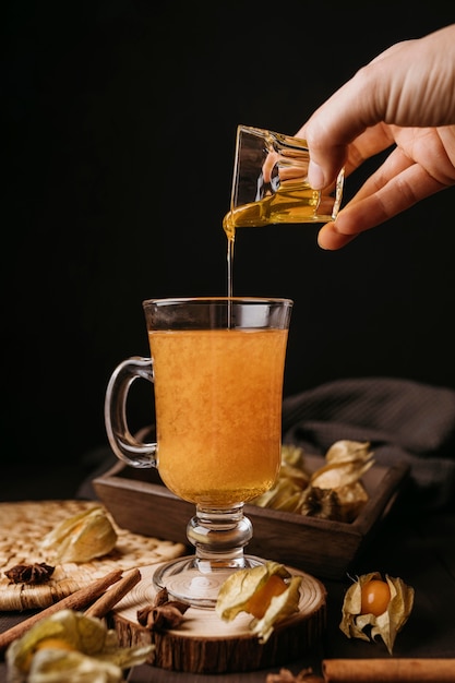 Front view hand pouring honey in winter hot drink