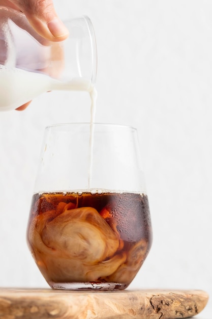 Free photo front view of hand pouring milk in coffee glasses with copy space