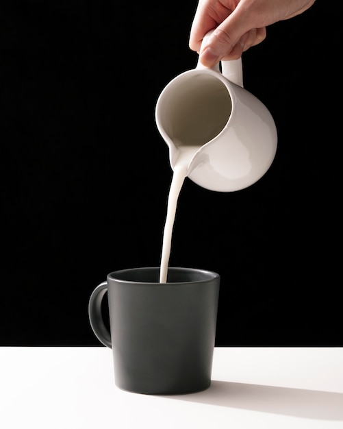 マグカップに牛乳を注ぐ手の正面図