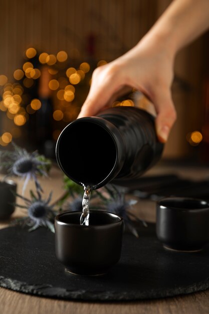 Front view of hand pouring sake drink