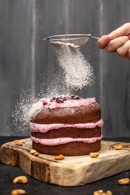 Front view of hand sieving powdered sugar on top of hands