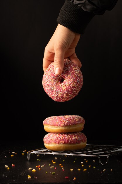 Front view of hand taking glazed doughnut from stack