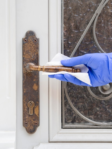 Free photo front view of hand with surgical glove cleaning door handle