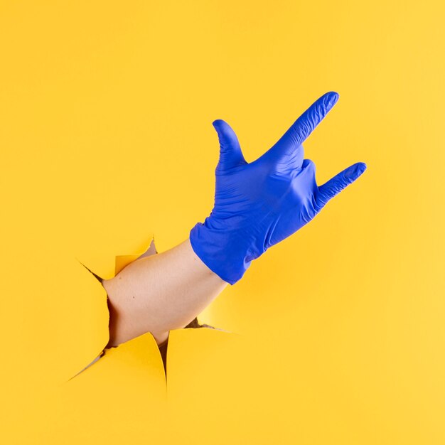 Вид спереди руки с хирургической перчаткой, показывающей жест рок-н-ролла