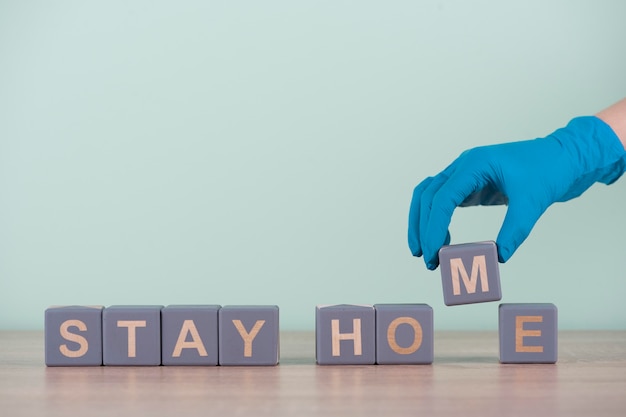 Free photo front view of hand with surgical glove and wooden cubes with stay home