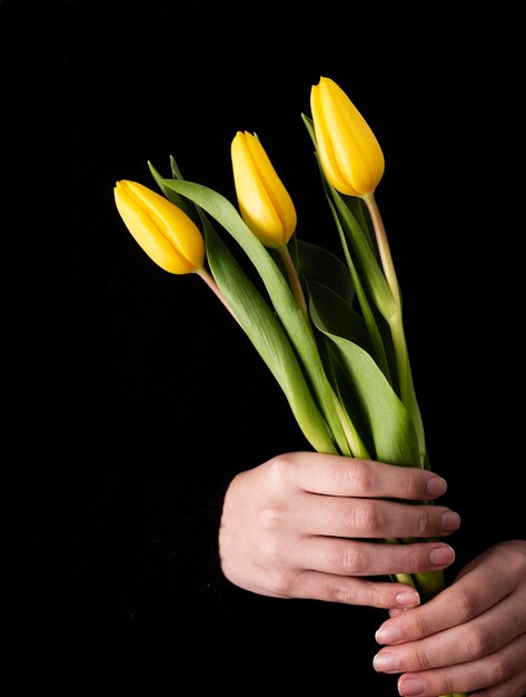 Вид спереди рука с желтыми тюльпанами
