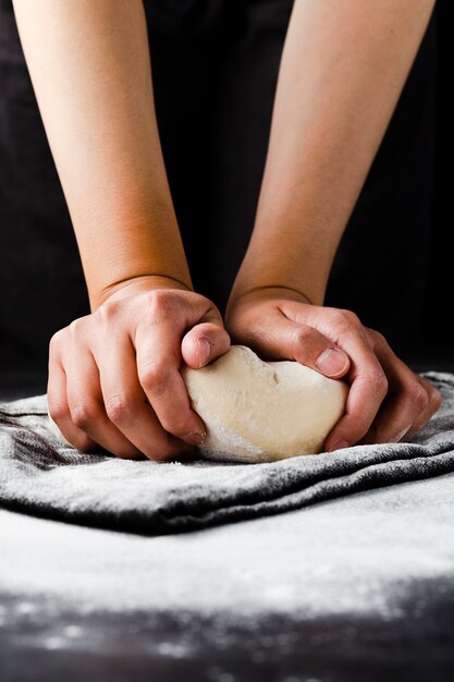 Front view of hands and dough with black background