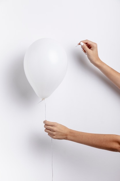 Front view of hands holding balloon with needle