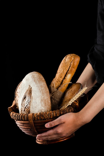 Front view of hands holding a basket with bread