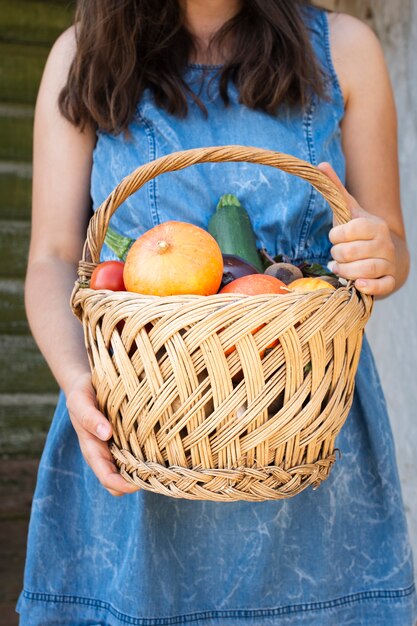 Front view hands holding basket with vegetables