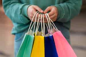 Free photo front view hands holding colorful paper bags