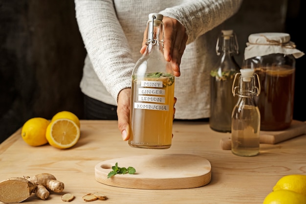 Foto gratuita mani di vista frontale che tengono la bottiglia di kombucha