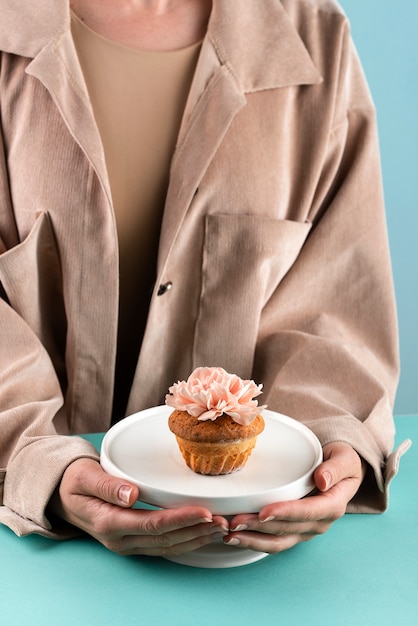 Front view hands holding platter with cupcake