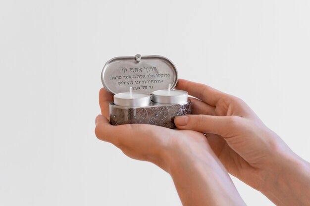 Front view of hands holding tea light candles for prayer